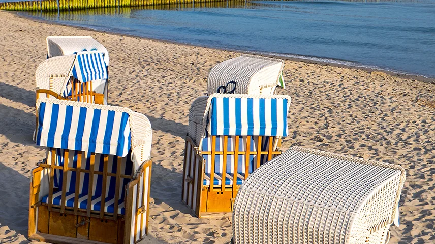 Klassiska strandstolar på en sandstrand på Östersjöns kust.