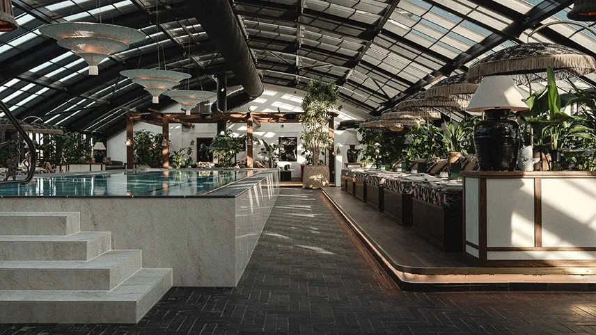 Hotellets inomhuspool i marmor, med marmortrappor och vackra sittgrupper samt gröna krukväxter runt.