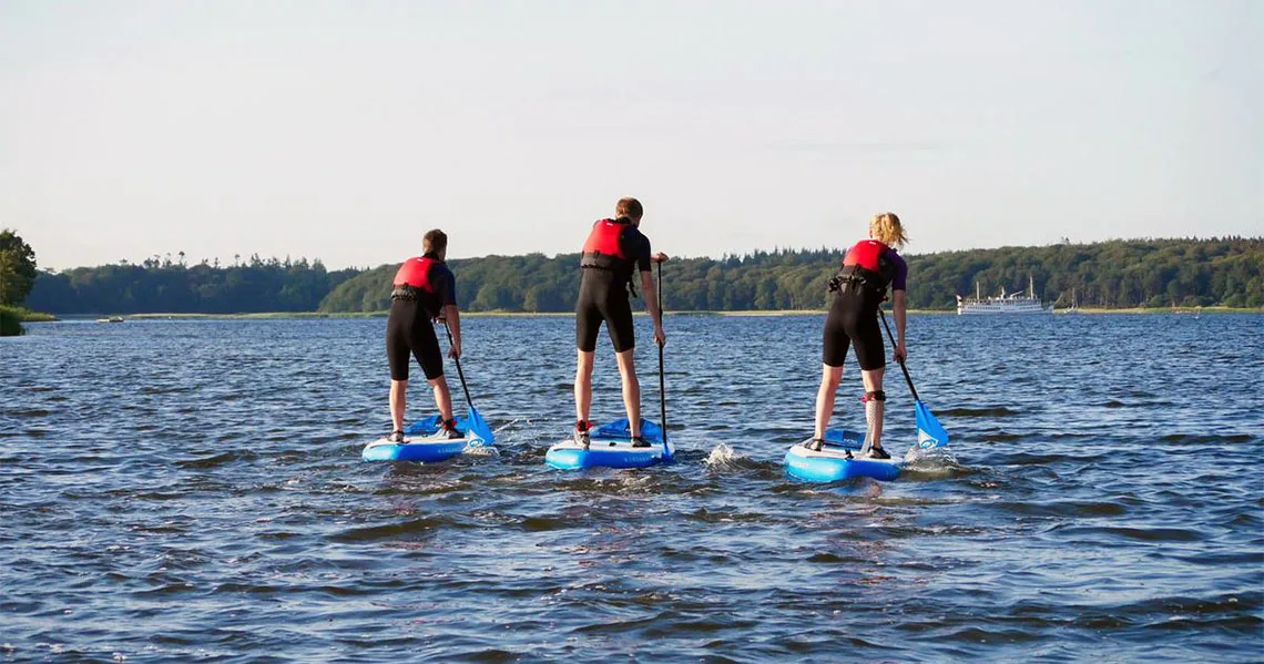 Tre personer som paddlar med SUP på vattnet utanför Roskilde.