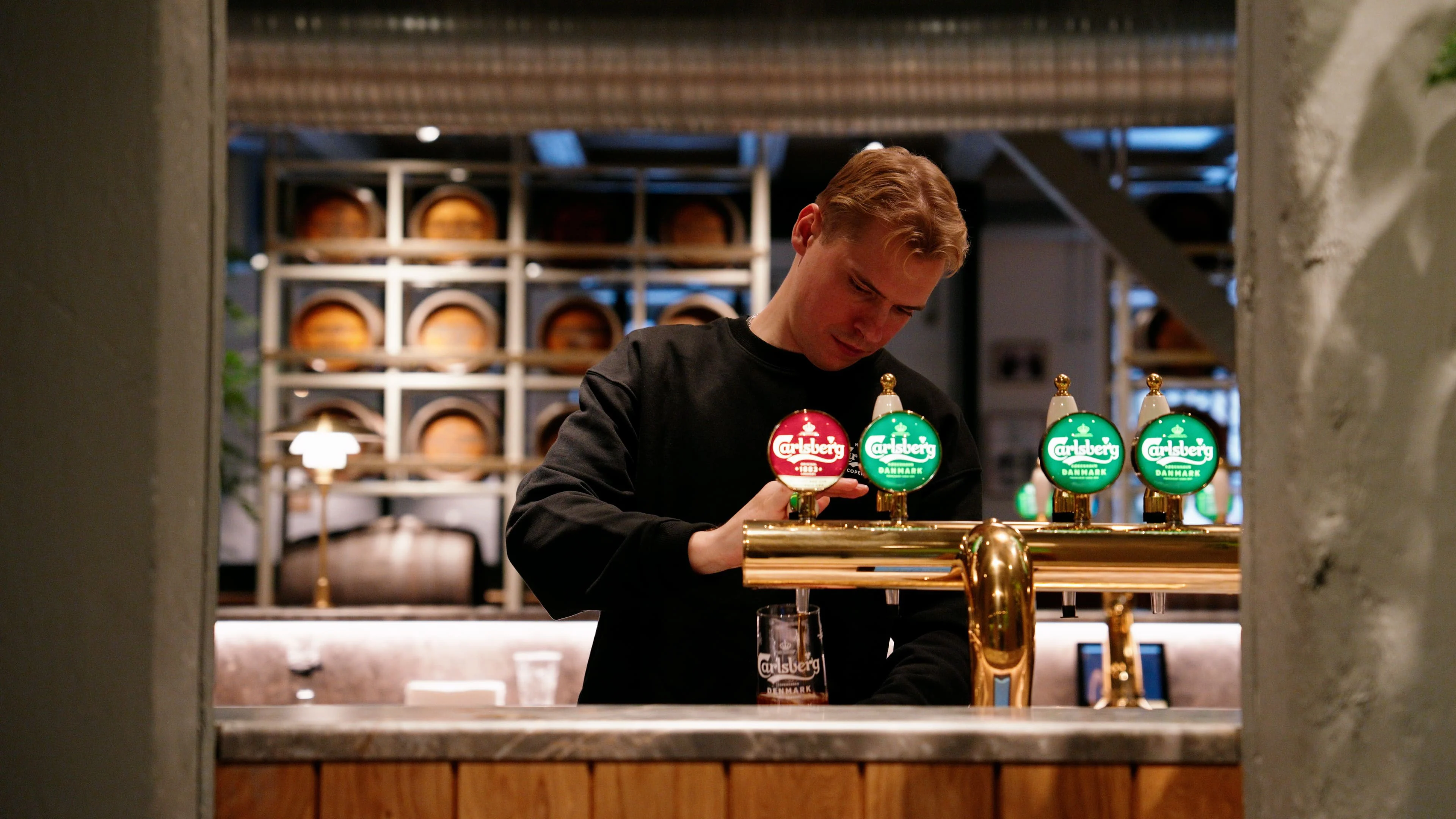 En bartender häller upp öl bakom disken i Carlsbergs bar.