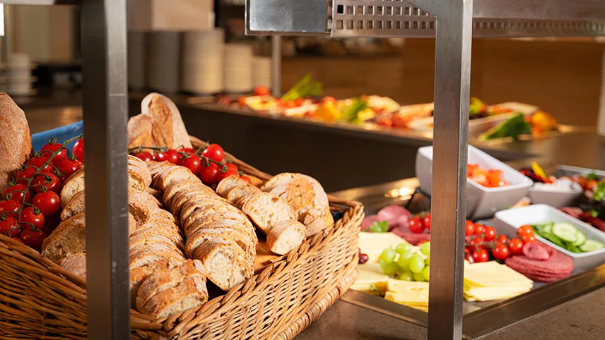 Frukostbuffén på strandhotellet. Man ser en brödkorg med färskt skivat bröd och röda kvisttomater samt stora brickor med ost, chark och grönsaker vackert upplagda.