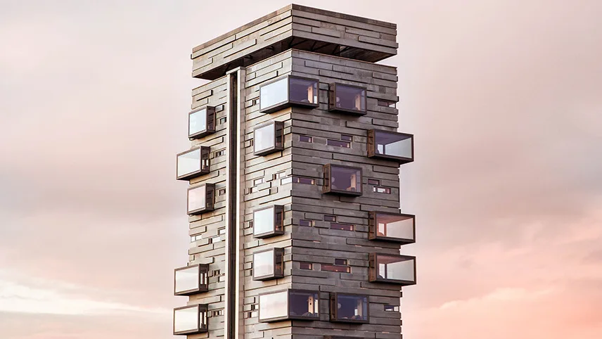 Hotellets torn sett utifrån mot en blek himmel. Det är skymning och det lyser i ett par av de stora panoramafönstren.