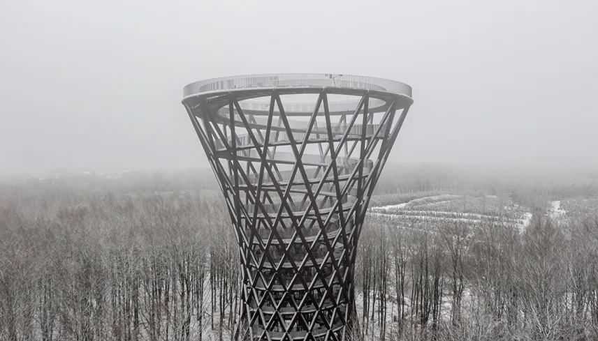 Skovtårnet i snöigt landskap med kala trädar och en blek vinterhimmel.