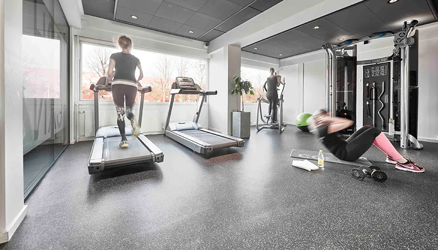 Hotellets gym med löpband, crosstrainer och hantlar. Flera gäster är i gång med att träna.