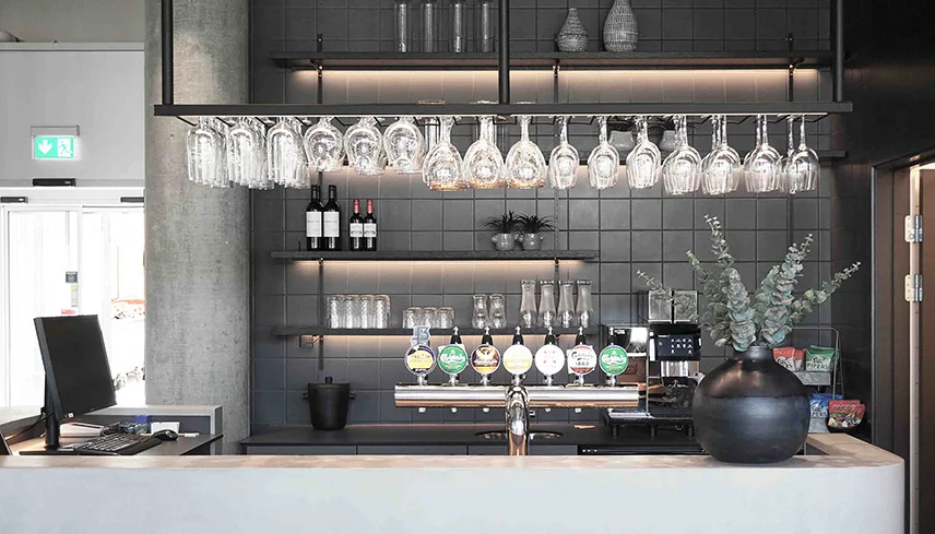 Hotellets bar med en bardisk, glas som hänger i taket och en lampa.
