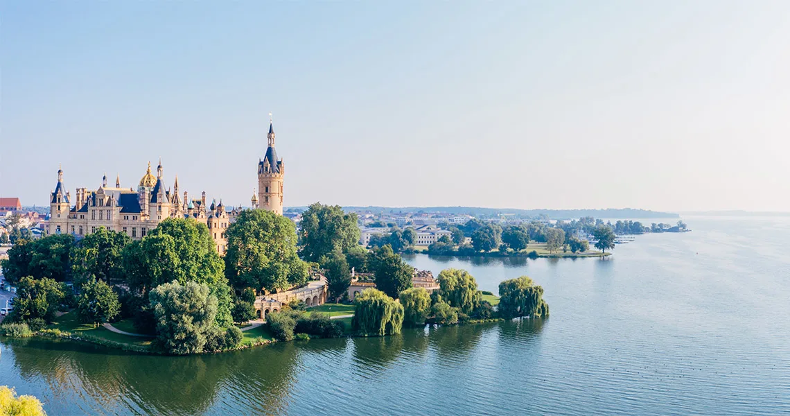 Flygfoto över Schwerins slott, beläget på en ö omgivet av vatten och lummiga träd