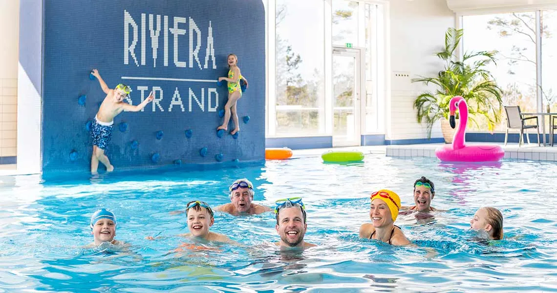 Børn og voksne svømmer i den indendørs pool på Riviera Strand.