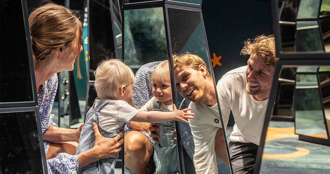 Litet barn och föräldrar leker bland speglarna på Experimentarium. 