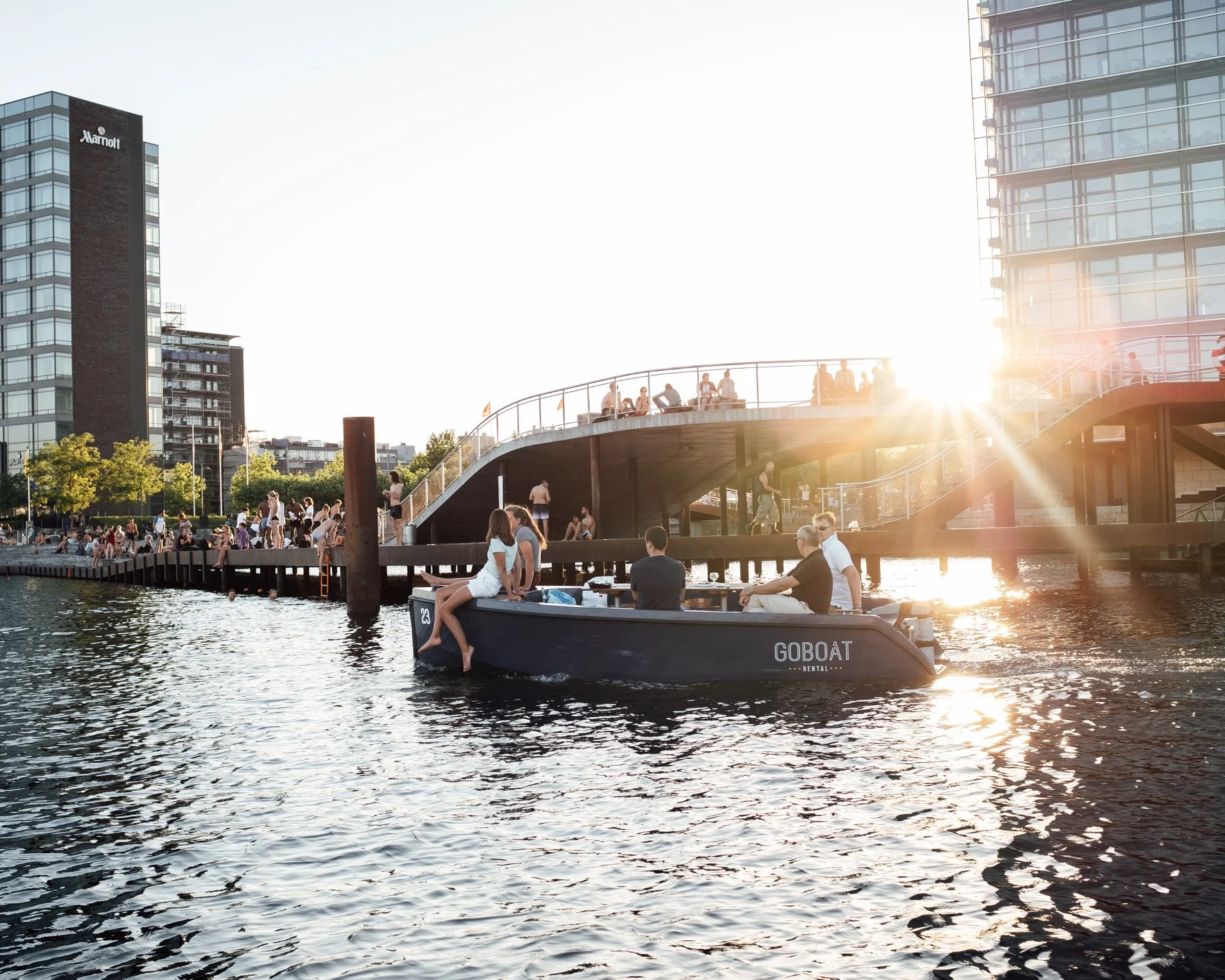 Människor som badar och kör en båt som man kan hyra av GoBoat i Köpenhamn.