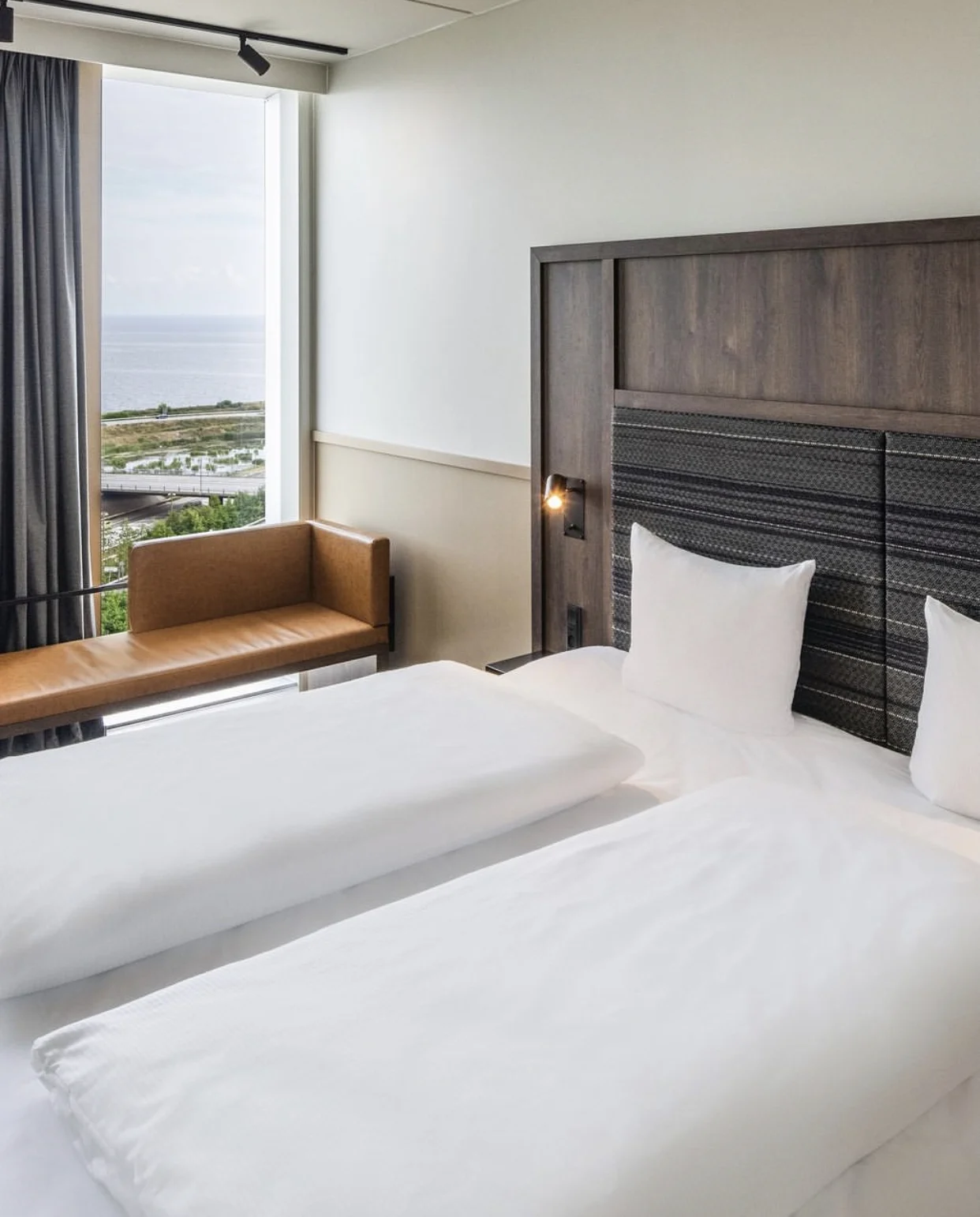 Hotellsäng med utsikt över strand och hav.