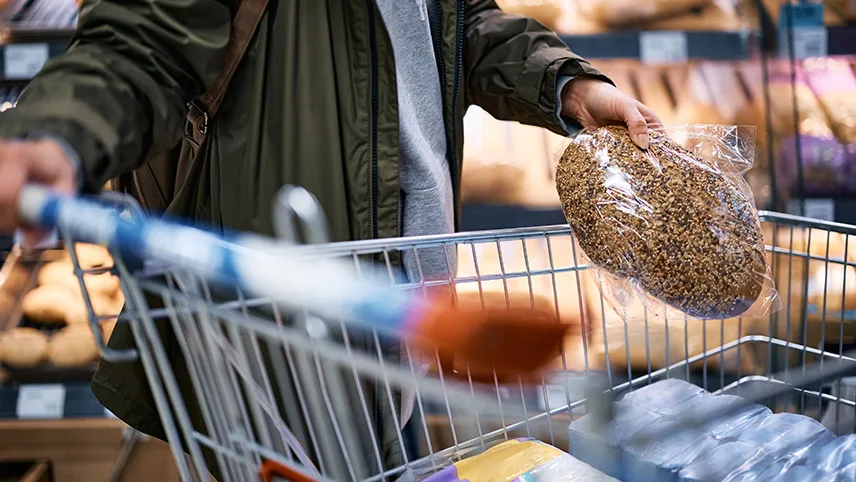 En kund lägger ett stort runt bröd i en kundvagn.