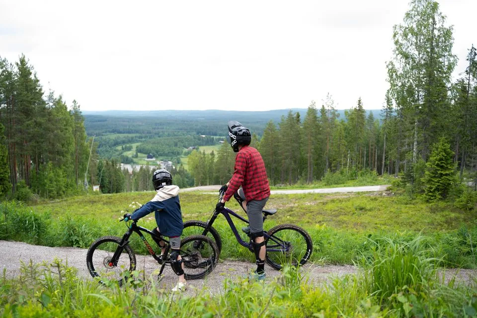 Børn og voksne står med cykler og kigger ud over Vallåsen.
