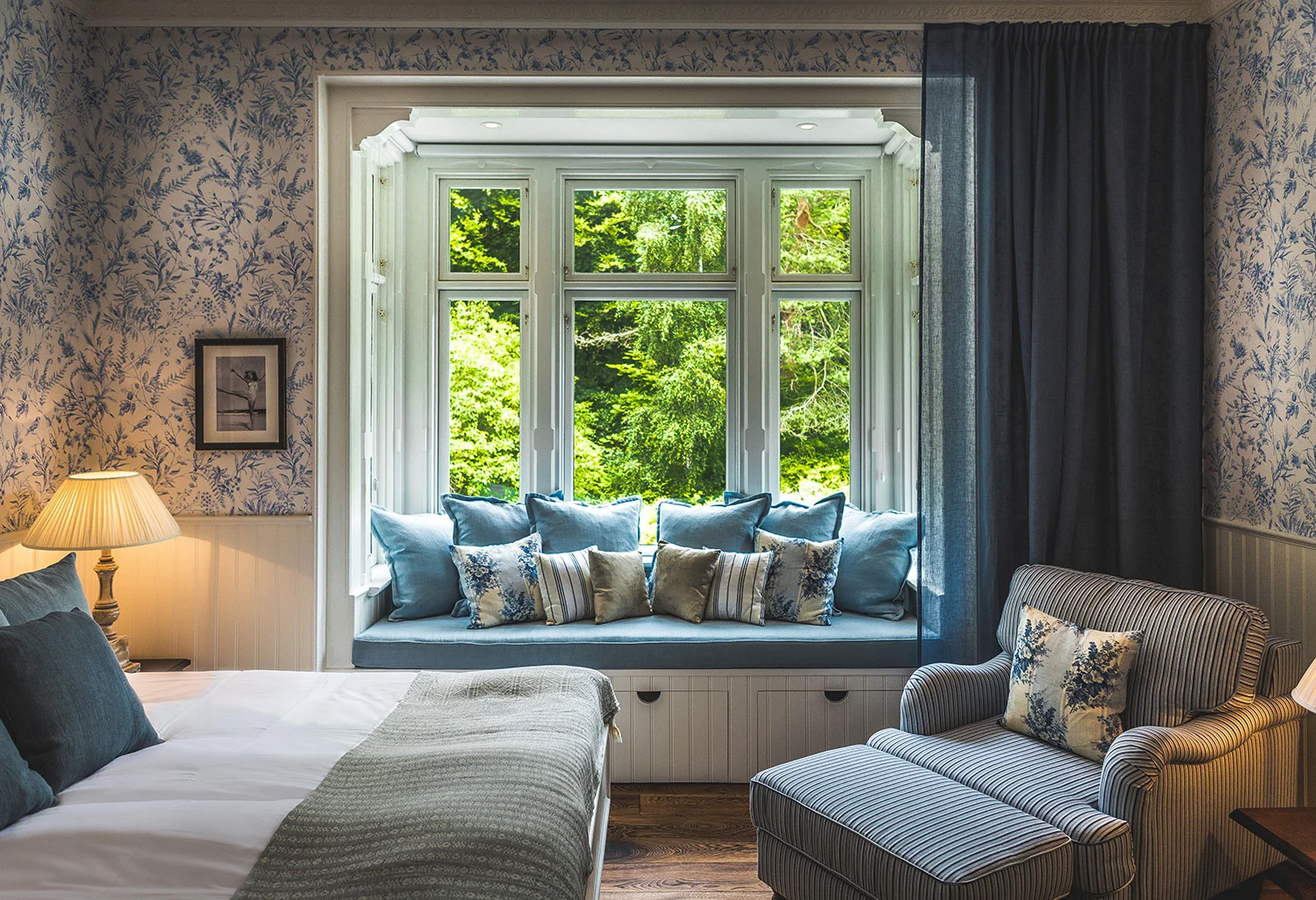 Værelse på Villa Strandvægen med seng, stol og hyggelig vindueskarm med puder.