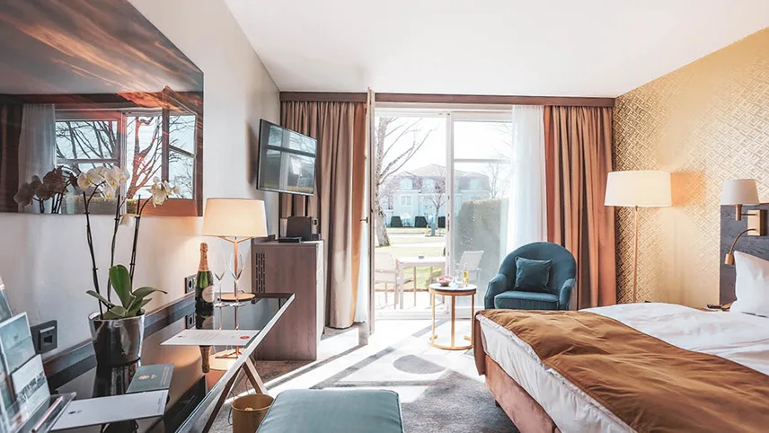 Ett av hotellets rum med stora fönster ut till en terrass, en bred dubbelsäng och vackra möbler.