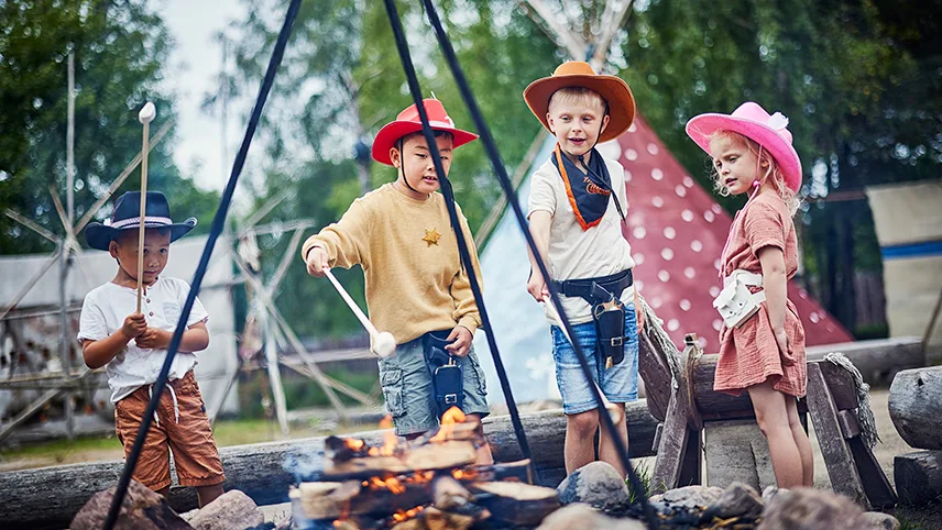 Bålstedet i High Chaparral i Småland, hvor fire børn iklædt cowvoyhatte står og griller snobrød.