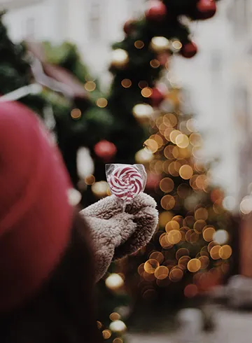 Hand med vantar som håller polkagris på julmarknad i Köpenhamn.