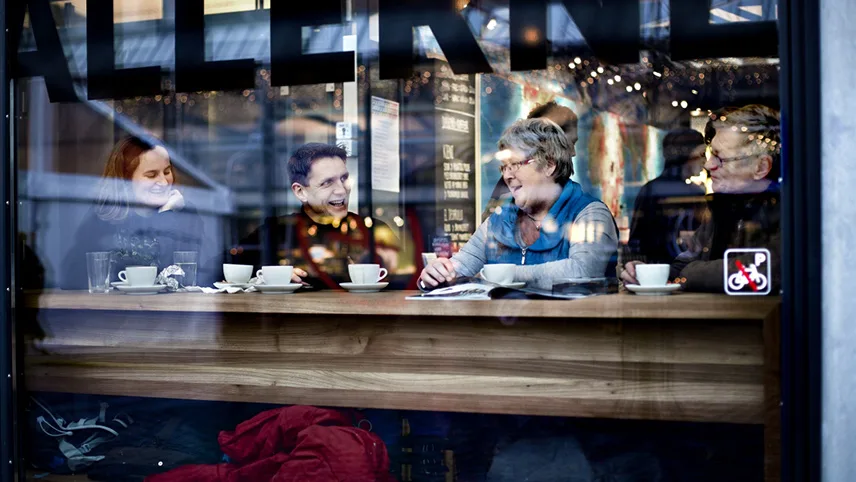 Gäster sitter vid en bardisk och dricker kaffe på Torvehallerne. 