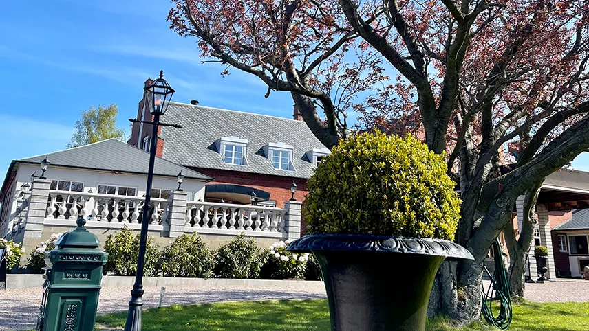 Forsiden af Villa Brunnby med blomstrende kirsebærtræer.