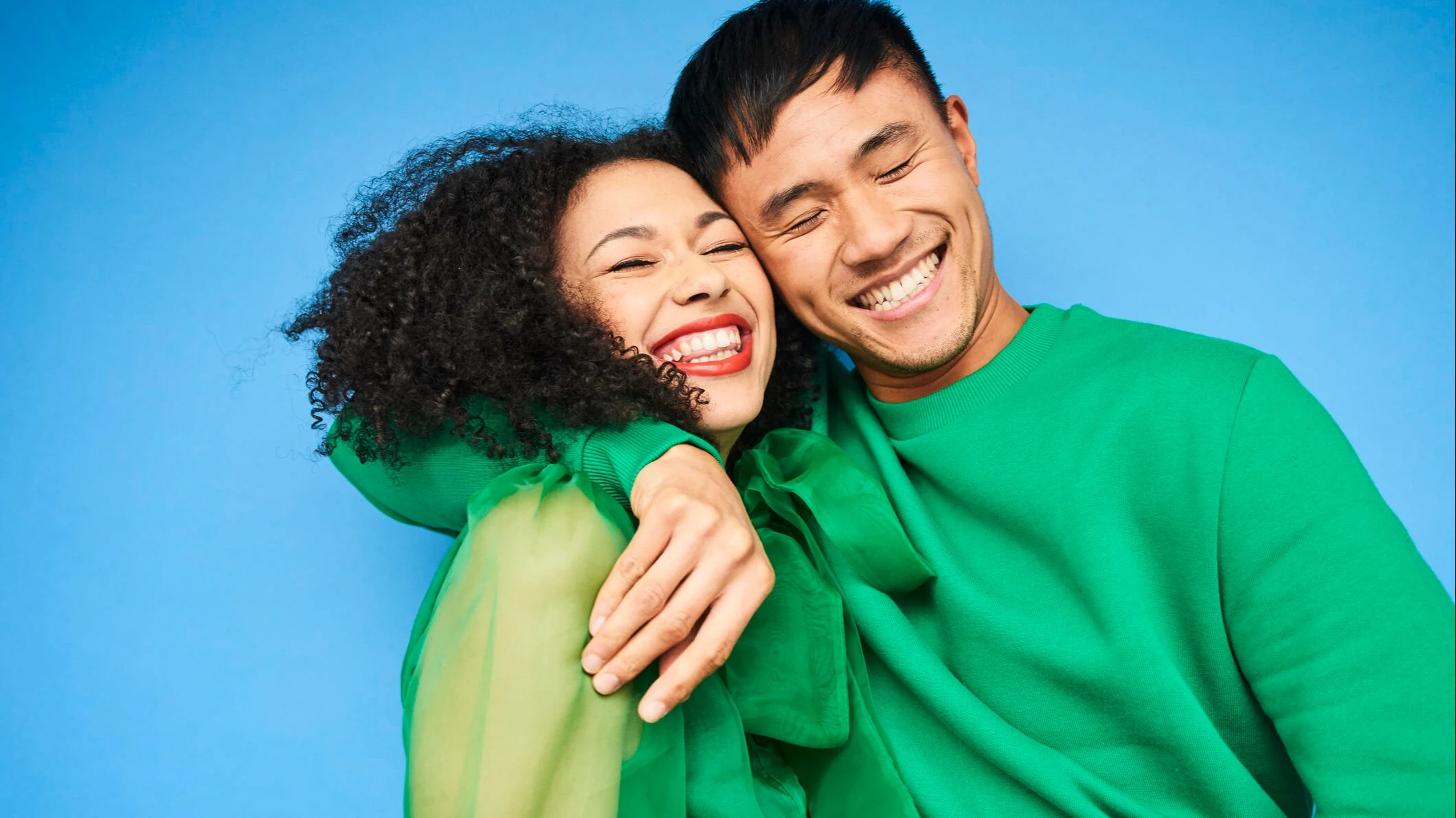 Ein lächelndes Päärchen, was sich in den Armen hält auf blauem Hintergrund