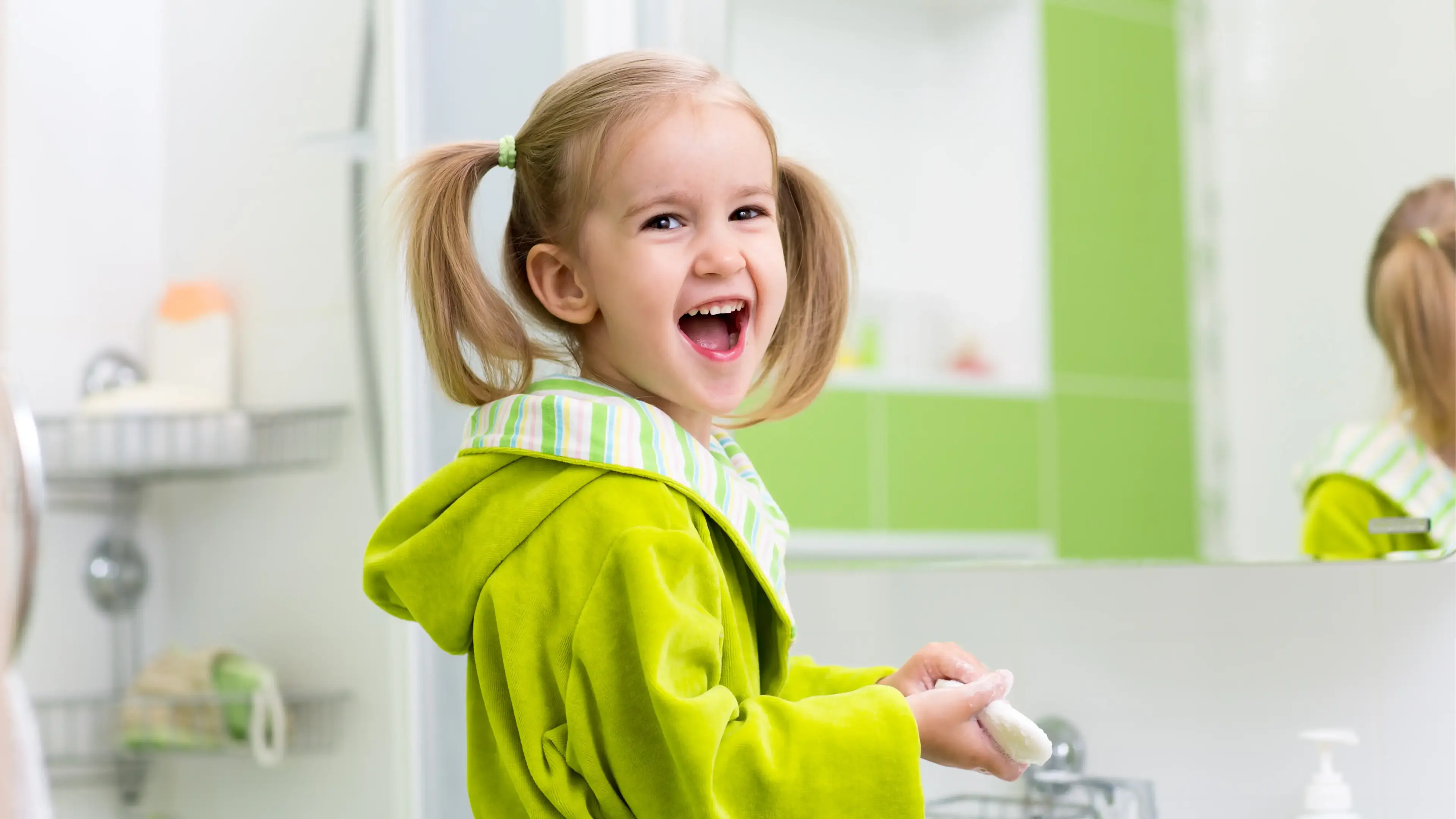 Ein lächelndes Kind mit Zöpfen im Bad