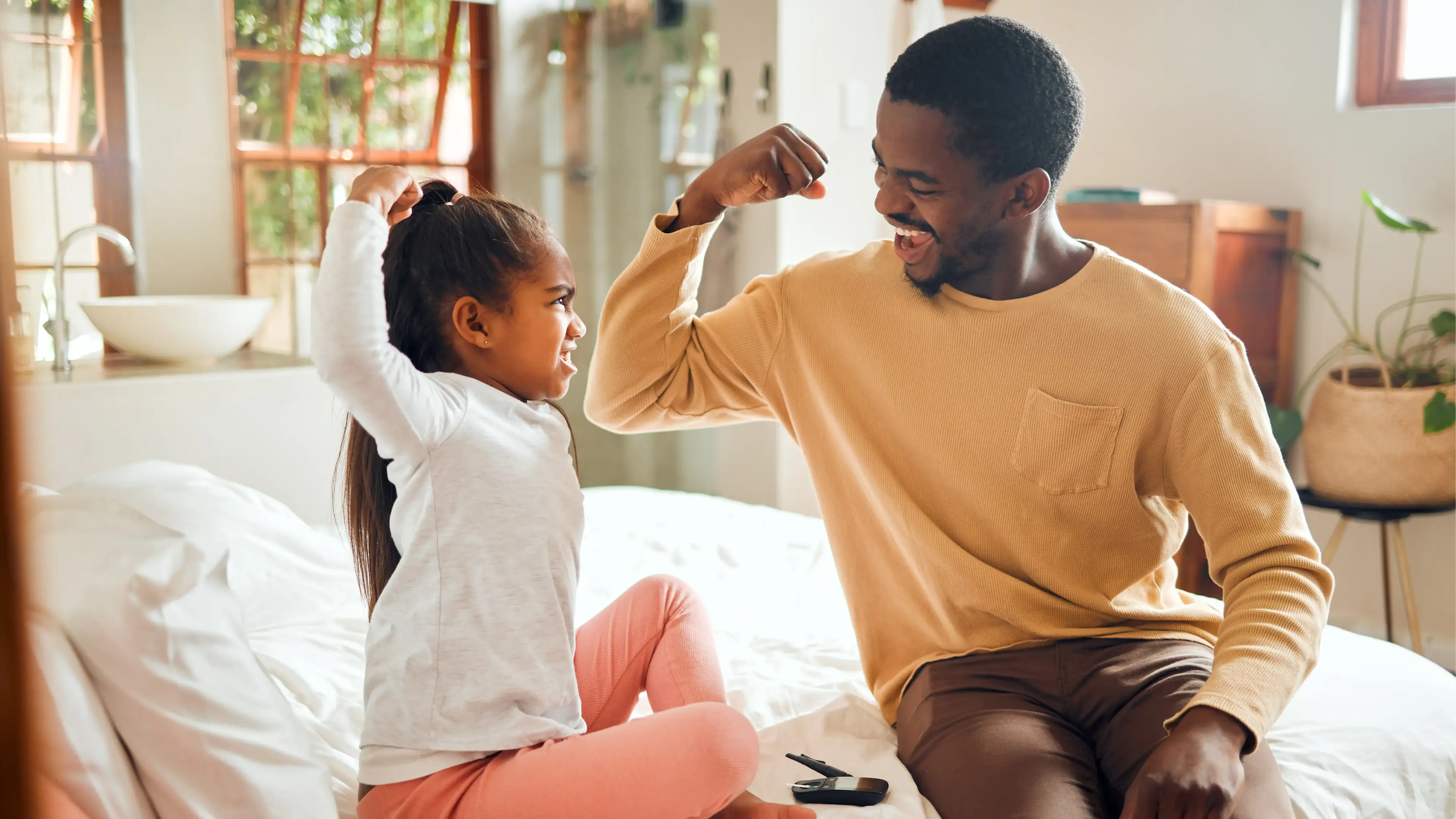 Ein Mann und ein Kind machen reißen spielerisch die arme zu einer Kraftpose hoch.