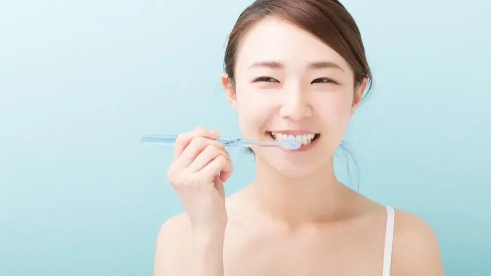 Eine asiatische jüngere Frau, die sich die Zähne putzt.