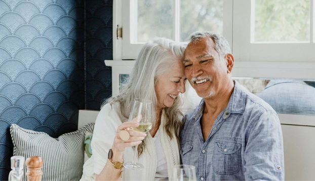 Elderly couple laughing over drinks