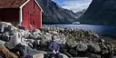 Young local boy watches as a Hurtigruten Expeditions cruise ship sails into Hjørundfjorden