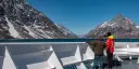 Two people standing on the outside deck looking at the mountains we're sailing by.