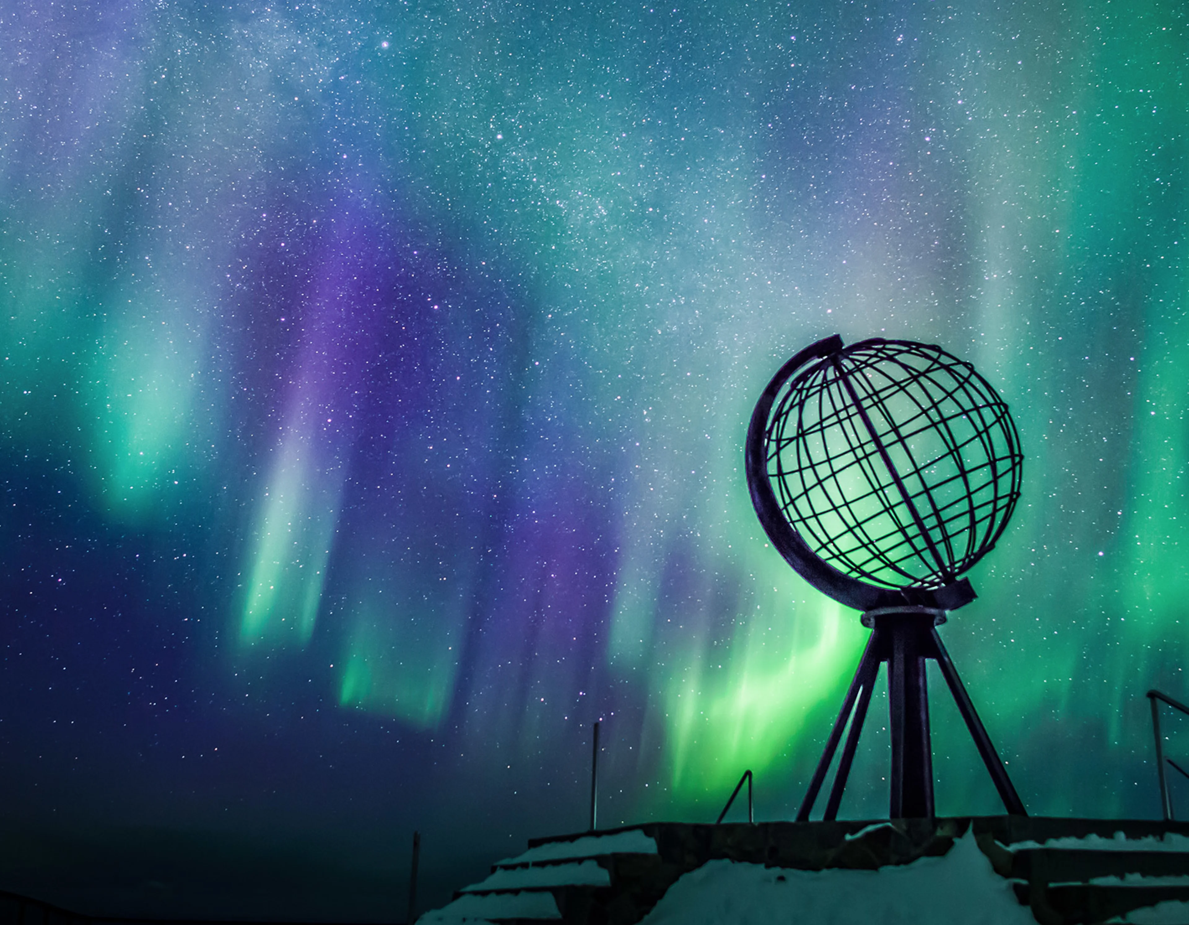 Globe monument set against the blue and green of the Northern Lights at the North Cape 