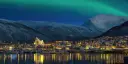 Tromsø in the dark with lighted houses and the church, northern lights in the sky.