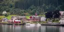 Red wooden houses and some boats along the Fjærlandsfjord in Norway.