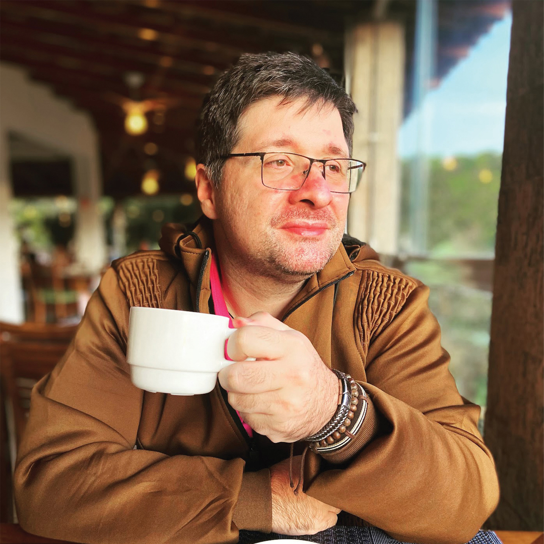 Homem usando óculos e segurando uma xícara de café.