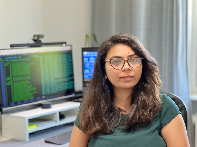 Femme avec des lunettes devant un écran d'ordinateur affichant des codes