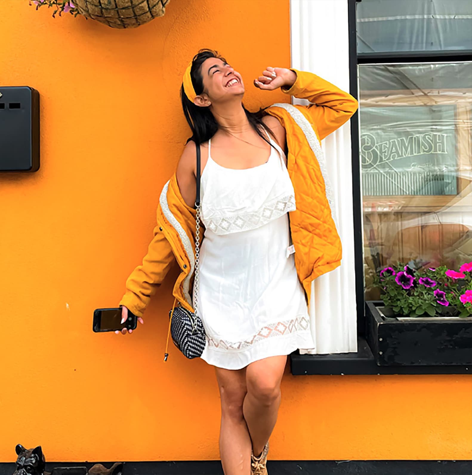 Woman looking up laughing while standing in front of a colorful wall