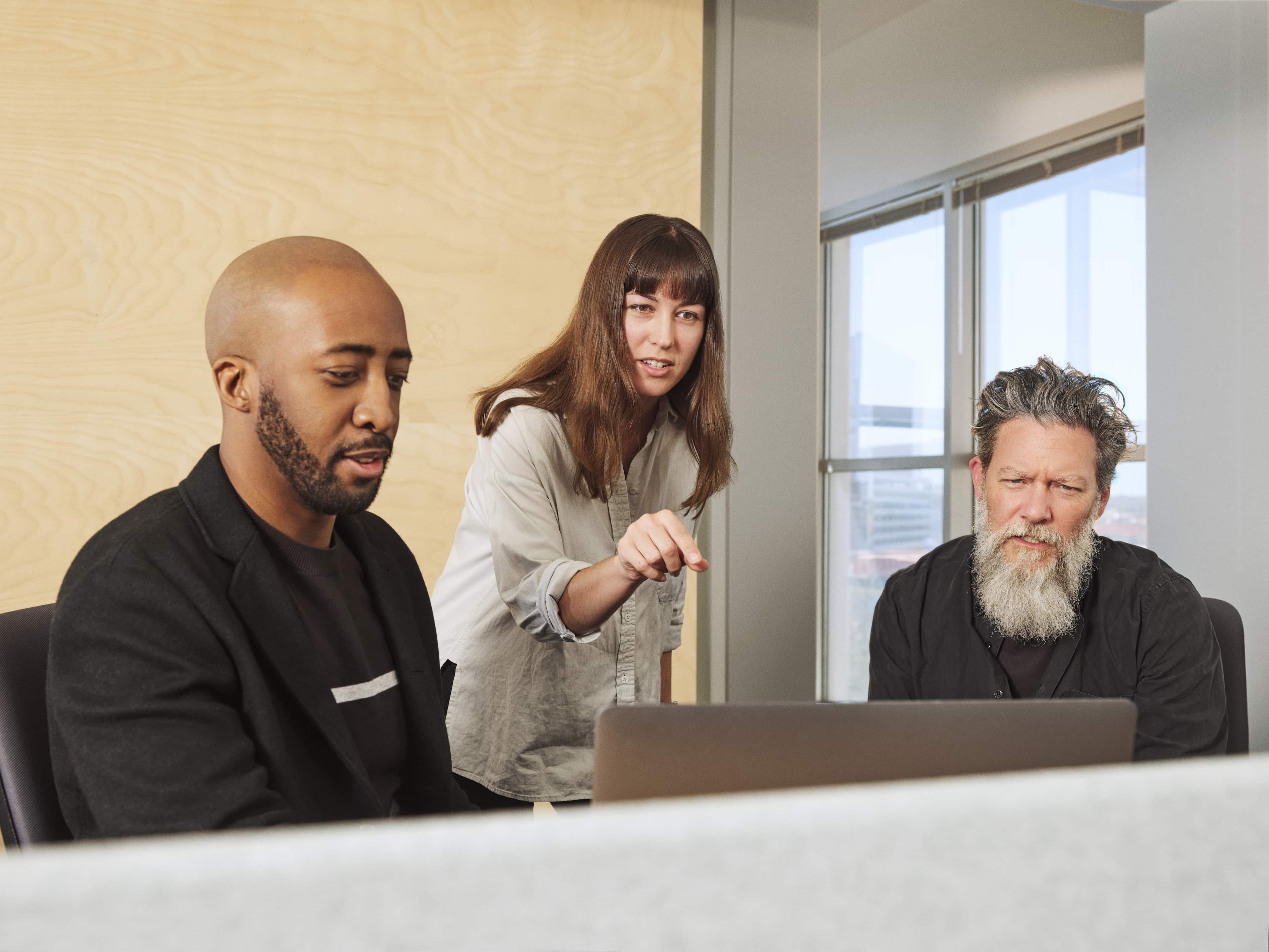 Três IBMistas trabalham juntos e estão discutindo algo em frente a um computador.