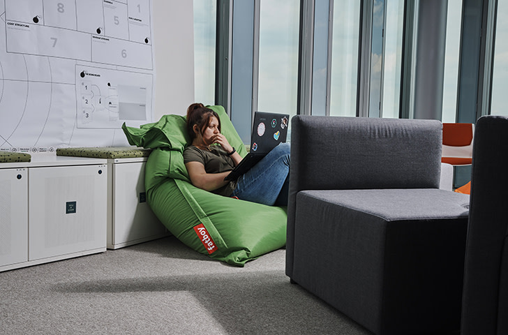 Young woman using laptop on a bean bag couch at the office