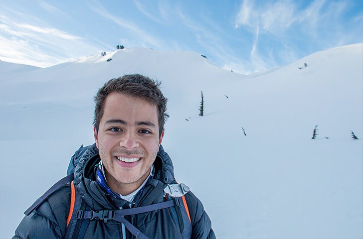 Young man smiling in front of snow.