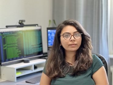 Mujer con gafas frente a la pantalla de la computadora que muestra código
