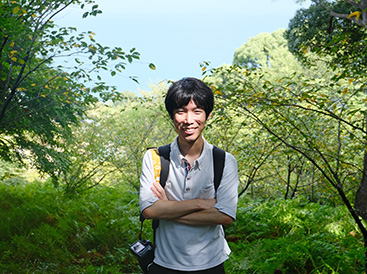 Man smiling, green nature in the background