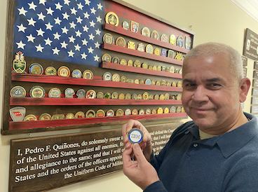 Man holding an IBM pin, medals in the background.