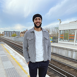 Man standing at a train station smiling to the camera