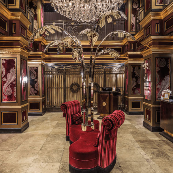 Luxurious art deco lounge with crystal chandelier, red velvet chairs, and metallic palm tree decor