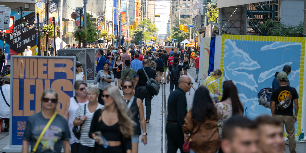 Looking down Festival Street with crowds of people and murals in the foreground