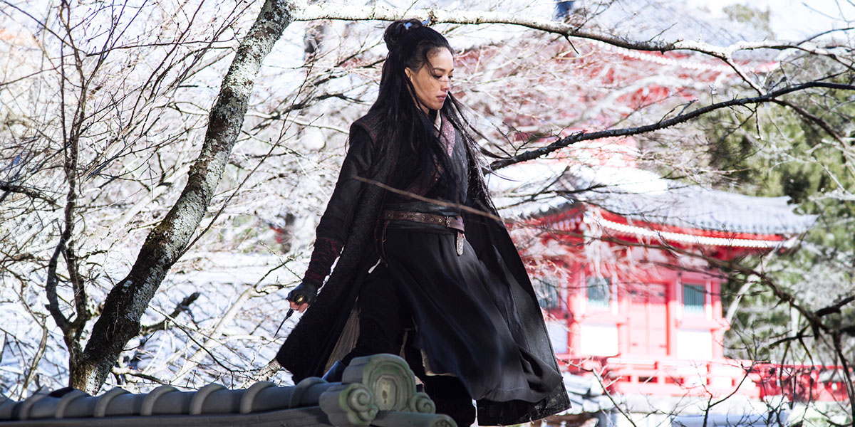 Assassin Nie Yinniang (Shu Qi) standing on a snow covered rooftop waiting for her target