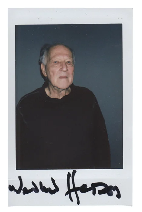 Polaroid photo of an elderly man in a black sweater with a signature at the bottom.