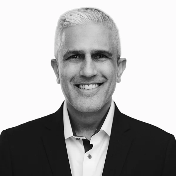 Black and white headshot of a smiling middle-aged man in a dark blazer and white shirt.