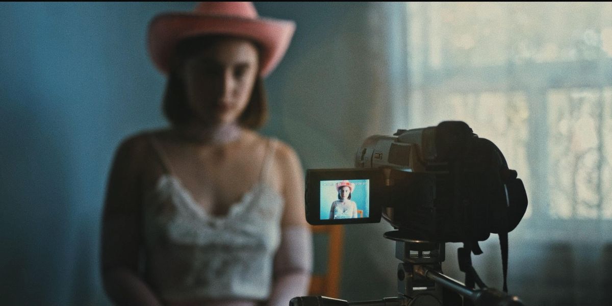 A woman standing out of focus in front of a video camera