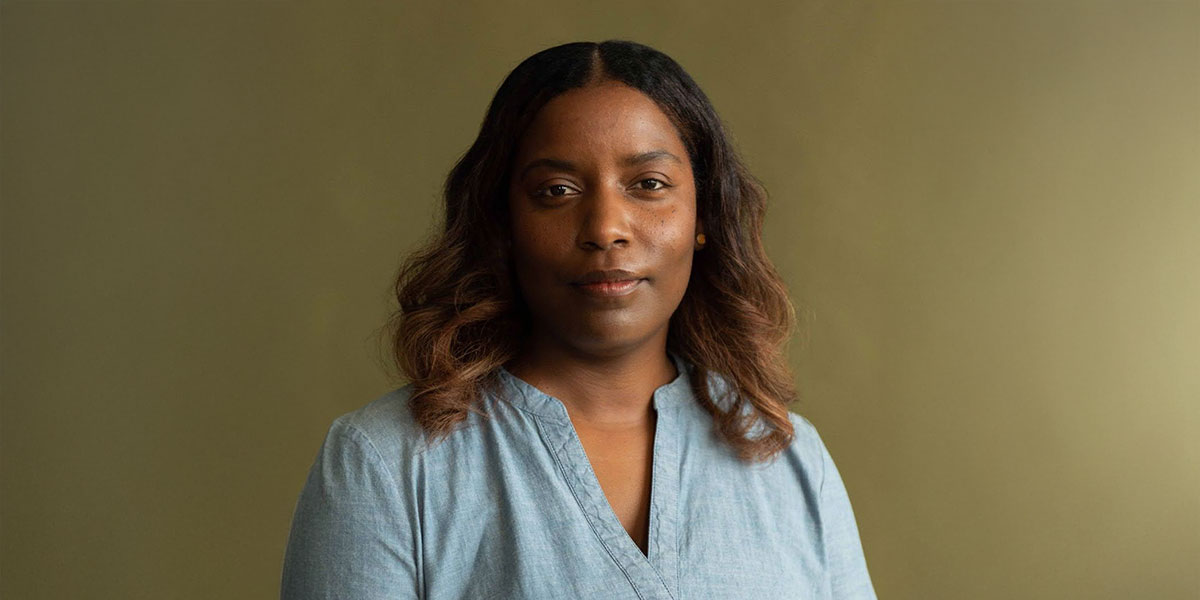 Portrait of Miyram Charles in a blue blouse against a green background. Photo credit: Claudie-Ann Landry