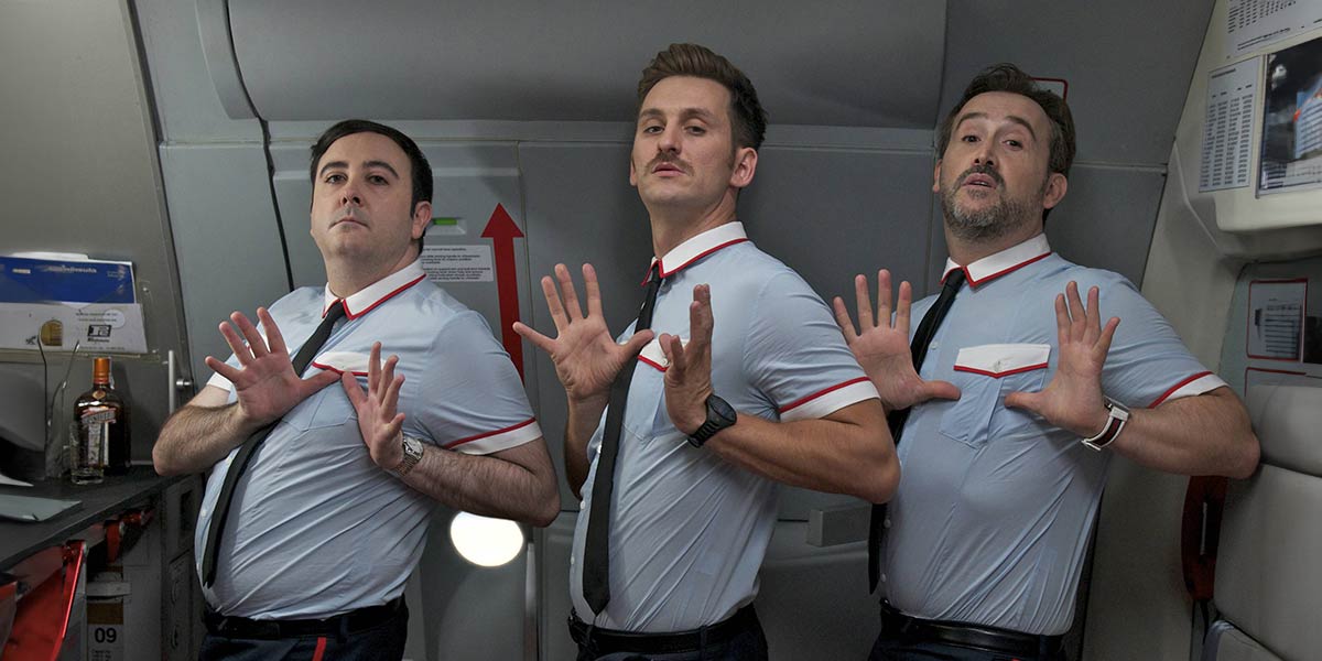 Three male airline attendants dancing in the kitchen cabin area